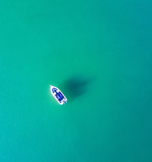 Aerial view of a small boat on clear turquoise water.
