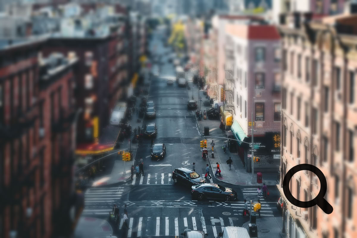 Aerial view of a busy urban street lined with brick buildings and vehicles.