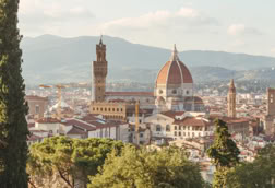 View of Florence with the Cathedral of Santa Maria del Fiore and surrounding buildings, framed by trees.